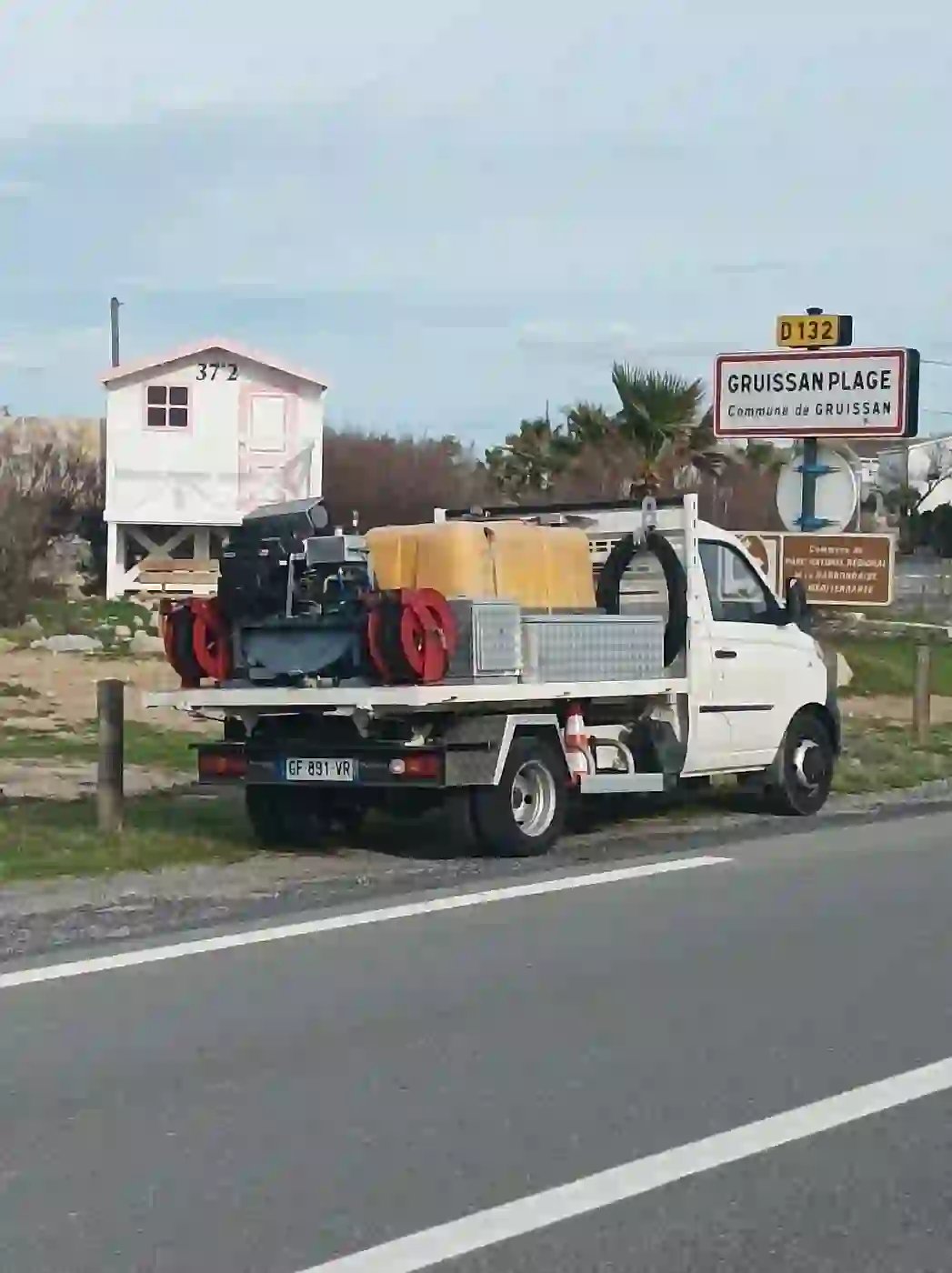 GRUISSAN Camion hydrocureur débouchage canalisation à Gruissan Plage avec panneau entrée et chalet emblématique
